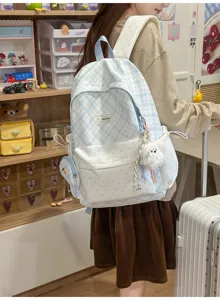 Vue de dos d’un sac à carreaux bleu et blanc, à empiècements à pois et avec un pendentif peluche