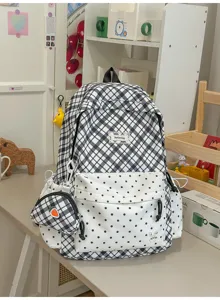 Sac à dos à carreaux noirs et blancs, à pois, avec mini-sac assorti et breloques posé sur un bureau