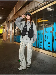 Street-style view of a person wearing a black utility vest over a gray sweatshirt in a shopfront setting