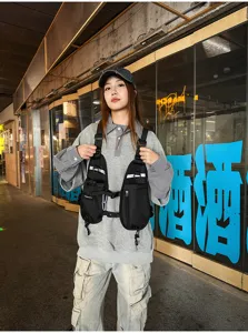 Street-style view of a model wearing a black multi-pocket chest bag with adjustable straps