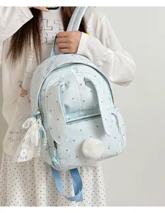 Une fille porte un sac à dos bleu clair à pois, avec oreilles de lapin, nœud en dentelle et perles