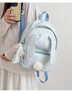 Gros plan sur un sac à dos bleu clair à pois, avec oreilles de lapin et pompon doux en dentelle