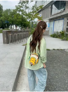 Petit sac jaune et crème porté dans le dos en extérieur, avec poche avant à fermeture éclair visible
