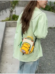 Vue de dos d'une personne portant un petit sac à cordon jaune, crème et vert, à bandoulière noire