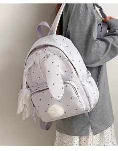 Porté par un modèle, sac à dos lilas clair à pois, oreilles de lapin et pompon moelleux