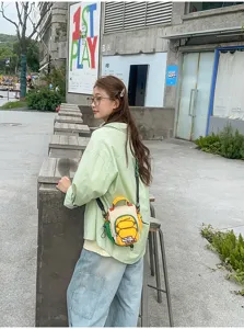 Scène de rue montrant une femme portant un petit sac bandoulière jaune, blanc et vert
