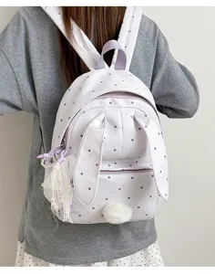 Sac à dos blanc à pois porté, avec oreilles de lapin, pompon et breloque en dentelle visible