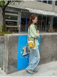 Vue de côté d’une personne portant un sac jaune en forme de pain, avec poignée et bandoulière