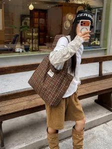 Brown plaid canvas tote carried over the shoulder in a casual café street-style scene