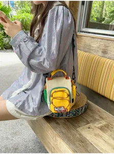 Vue portée au quotidien d’un sac jaune et crème avec poche à cordon sur le devant, en bandoulière