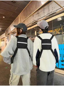 Rear view of two people wearing black nylon chest bags with adjustable straps and white reflective bands