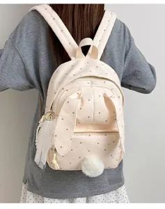 Vue de dos d’un sac à pois avec oreilles de lapin et pompon doux, porté sur les épaules