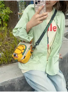 Selfie en extérieur montrant un modèle portant un sac jaune et beige à bandoulière sombre réglable