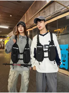Two models wear black chest packs with zip pockets and reflective strips in a street setting
