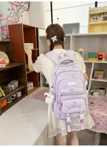 Vue de dos d’une élève portant un sac lavande à étoiles, avec poches zippées et charm en peluche