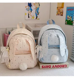Sacs à dos rose et bleu présentés côte à côte, à pois, avec oreilles de lapin et pompons doux