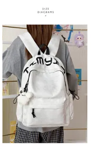 Vue arrière d’un sac à dos blanc, avec étoiles en relief, lettrage noir et petit ours en peluche visible