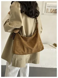 Vue arrière d’une femme portant un sac brun effet daim, avec sangle en cuir et boucle métal