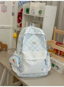 Carreaux et pois bleus et blancs, avec pochette latérale et breloque lapin, posé sur un bureau.