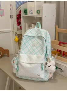 Vue rapprochée d’un sac à dos vert menthe à carreaux, poche à pois et ourson en peluche accroché