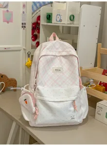 Vue de face d’un sac à dos rose à carreaux et pois blancs, avec broderie de lapin et pochette carotte