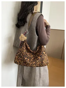 Vue latérale d’une personne avec un sac léopard spacieux et un porte-clés ourson en peluche