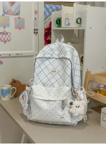 Sac à dos à carreaux bleu et blanc, à pois, avec breloque et poche latérale, posé sur un bureau
