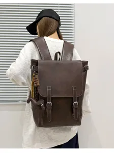 Rückansicht einer Person mit braunem Kunstlederrucksack, Überschlag und Riemen mit Schnallen