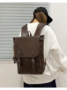 Rückansicht einer Person mit braunem Kunstlederrucksack, Überschlag, Schnallenriemen und Anhänger