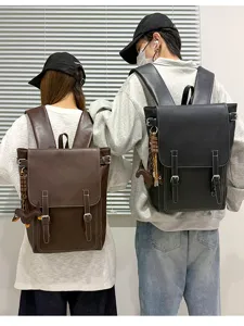 Zwei Personen von hinten mit braunen und schwarzen Rucksäcken mit Klappe, Schnallen und Anhängern