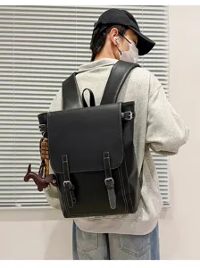 Person von hinten mit schwarzem Kunstlederrucksack, Überschlag, Schnallriemen und Tieranhänger