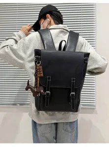 Rückansicht eines schwarzen Kunstlederrucksacks mit Metallschnallen und baumelnden Anhängern