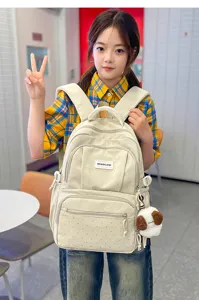 Modèle avec sac à dos crème à pois, poches zippées devant et pendentif ours en peluche