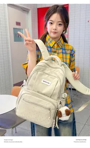 Une élève présente un sac crème à reliefs argentés en pois, avec un pendentif ourson en peluche