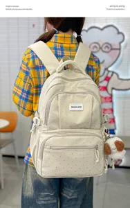 Vue de dos, sac à dos crème à pois porté avec un ours en peluche et des poches zippées