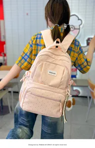 Vue arrière d’un modèle portant un sac à dos rose à pois, avec poches zippées et breloques