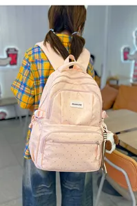 Vue de dos d’un sac rose à pois, avec poches zippées à l’avant et petit pendentif en peluche