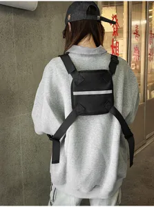 Back view of a model wearing a black nylon chest pack with an X-shaped harness and reflective strip