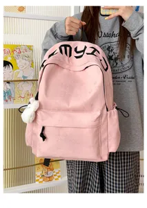 Sac à dos rose porté par un modèle, avec étoiles en relief, poche avant, inscription noire et pompon blanc