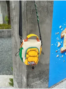 Vue extérieure d’un sac bicolore à poches zippées, poignée jaune et bandoulière noire réglable