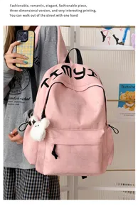 Détail d’un sac à dos rose, avec étoiles embossées, lettrage noir et pendentif en peluche blanche