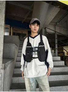 Model wearing a black tactical chest bag with adjustable straps, front pockets and zip closures