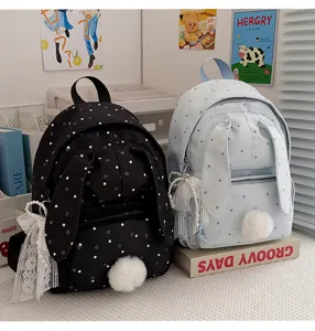 Deux sacs à dos à pois côte à côte, avec oreilles de lapin, pompons, dentelle et breloques perlées