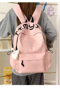 Vue de dos d’un sac à dos rose à motif étoilé, lettrage noir et ourson en peluche accroché