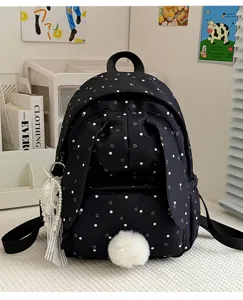 Vue de face du sac noir à pois et cœurs blancs, avec pompon doux et breloque à pampilles perlées