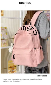 Sac à dos rose porté, avec étoiles en relief, lettrage noir et breloque blanche en peluche.