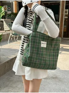 Street-style view of a green plaid tote bag with woven label, carried over the shoulder outdoors