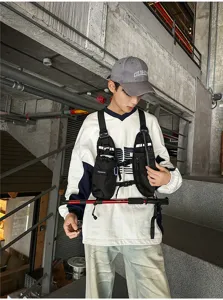 Person wearing a black multi-pocket chest rig with adjustable straps on industrial stairs