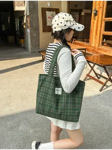 Street-style view of a model carrying a green plaid fabric tote over her shoulder outdoors