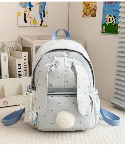 Vue de face du sac, avec tissu à pois, oreilles de lapin, pompon doux et chaîne ornée de perles